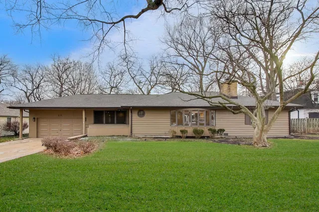 a front view of a house with a garden and trees