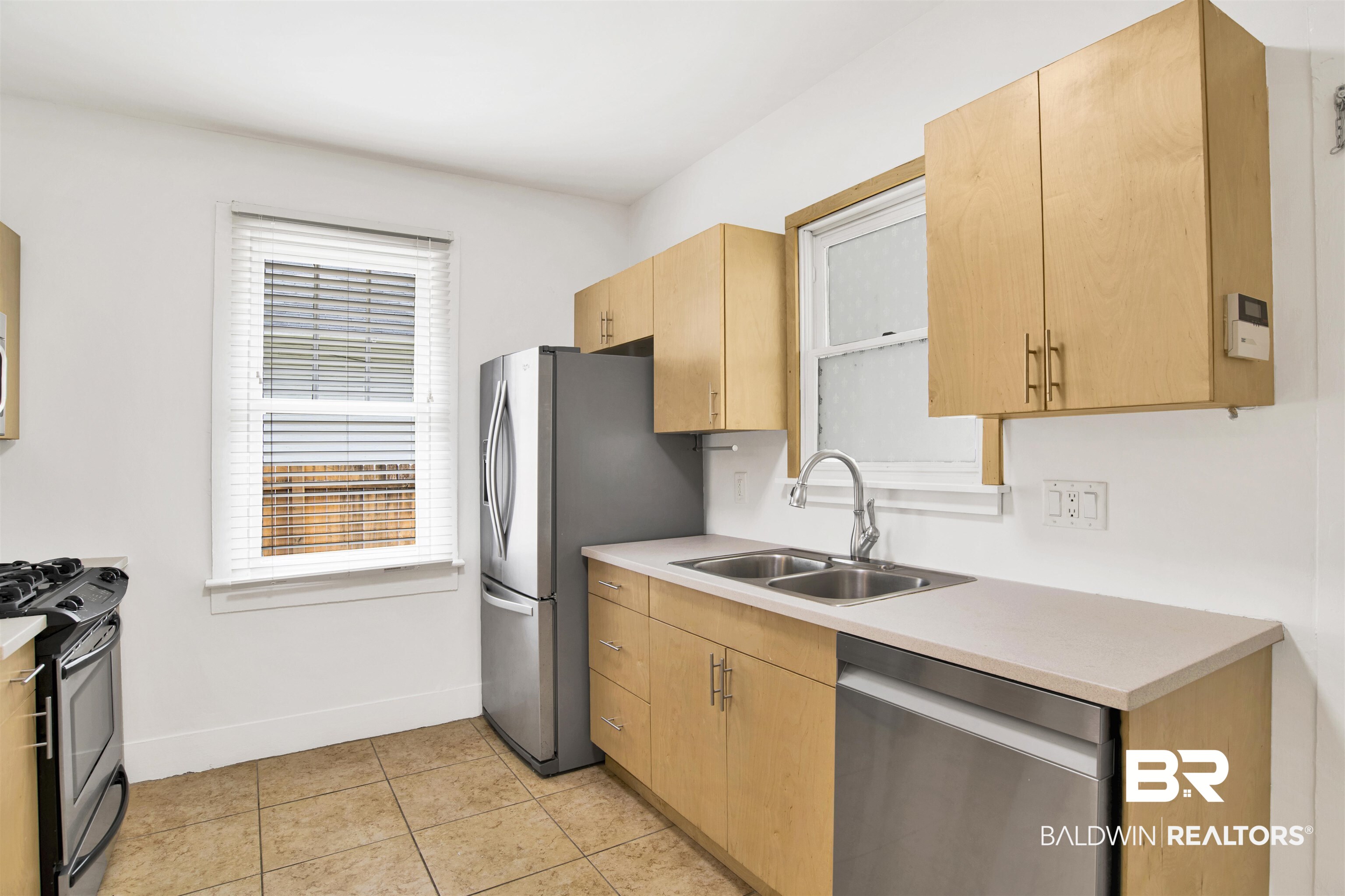 507 Holcombe Avenue Mobile, AL 36606 - Photo 12 of 28 Kitchen featuring stainless steel appliances, a sink, light countertops, light brown cabinetry, and baseboards