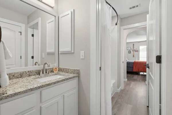 a en suite bathroom with a granite countertop sink and a mirror