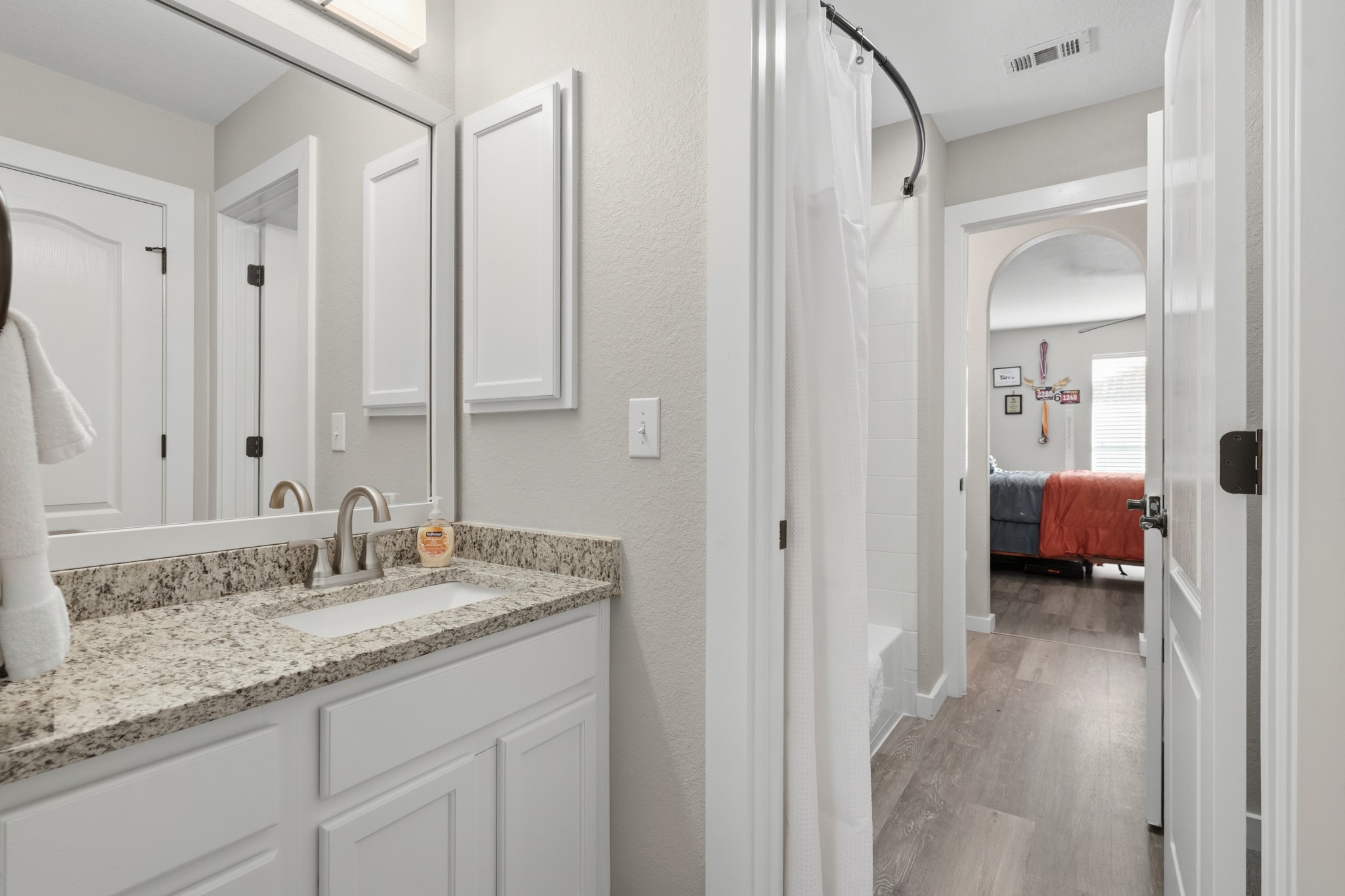 13922 Jubilee Way Helotes, TX 78023 - Photo 16 of 27 Jack and Jill style bathroom with separate vanities, light wood-style flooring, ensuite bath, shower / bath combo