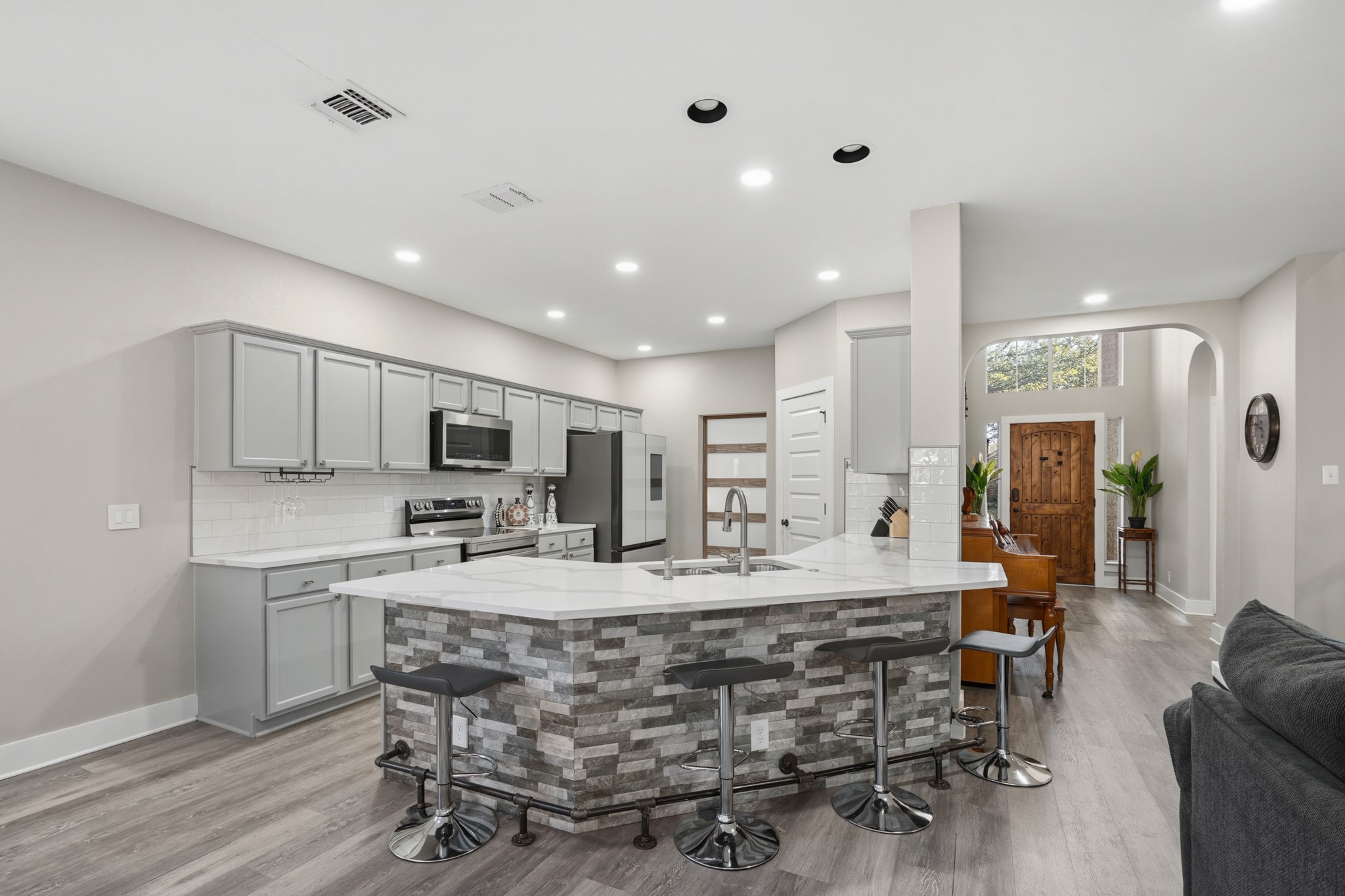 13922 Jubilee Way Helotes, TX 78023 - Photo 5 of 27 Kitchen featuring arched walkways, backsplash, gray cabinetry, a kitchen bar, and recessed lighting
