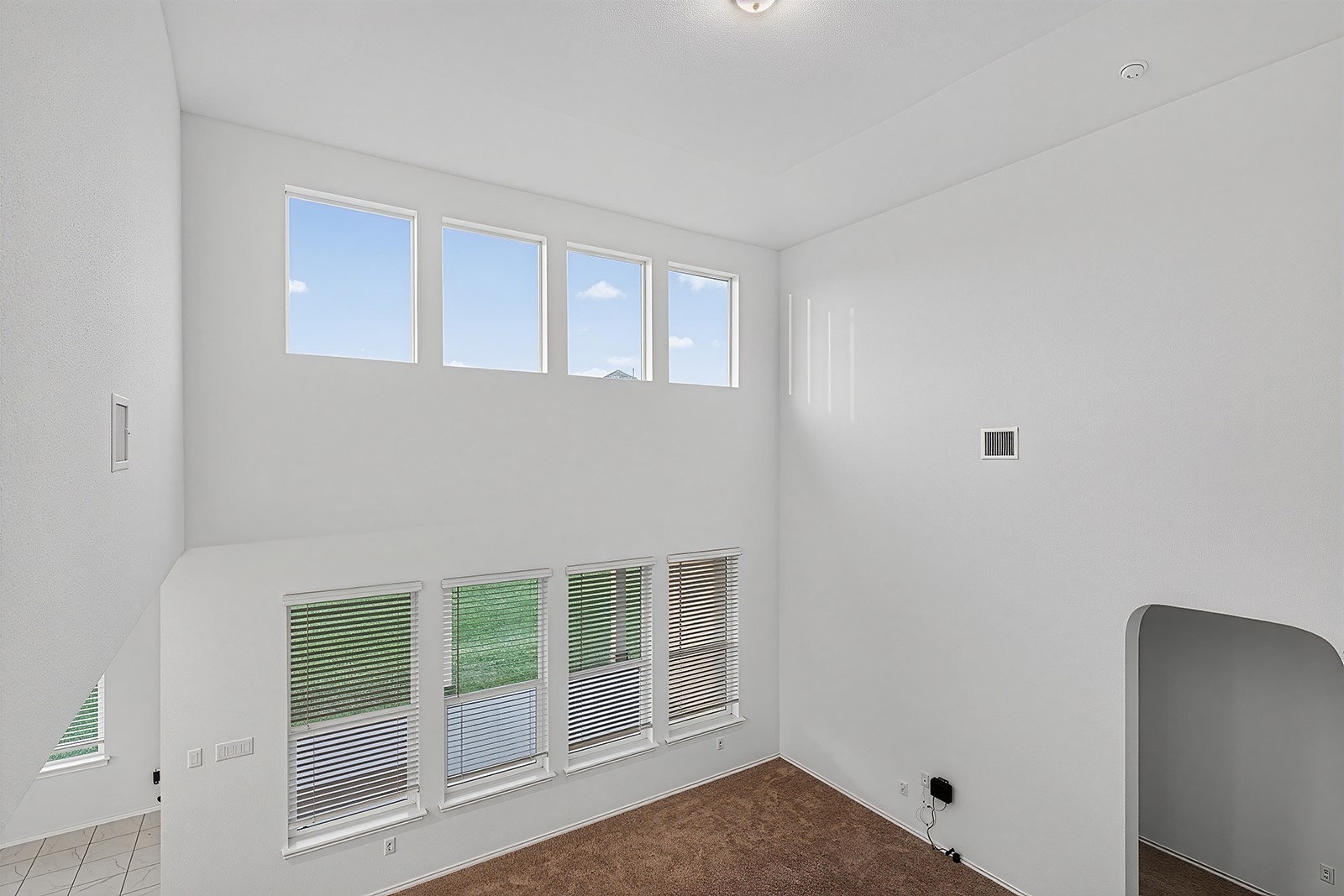4600 Ercolano Lane Round Rock, TX 78665 - Photo 23 of 37 Two-story interior space featuring high ceilings, multiple upper-level windows, lower-level windows with blinds, and brown carpet flooring