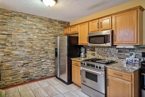 a kitchen with granite countertop a stove top oven microwave and cabinets