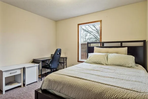 a bedroom with a bed a desk and a dresser next to a window