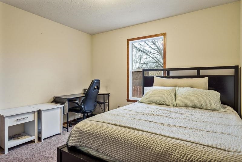 5094 Grand Cape Road Rockford, IL 61109 - Photo 22 of 30 a bedroom with a bed a desk and a dresser next to a window