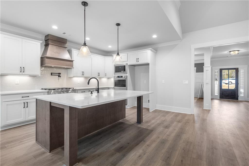 2321 Pebble Trail Monroe, GA 30656 - Photo 7 of 21 a kitchen with stainless steel appliances granite countertop a sink a stove and a wooden floors