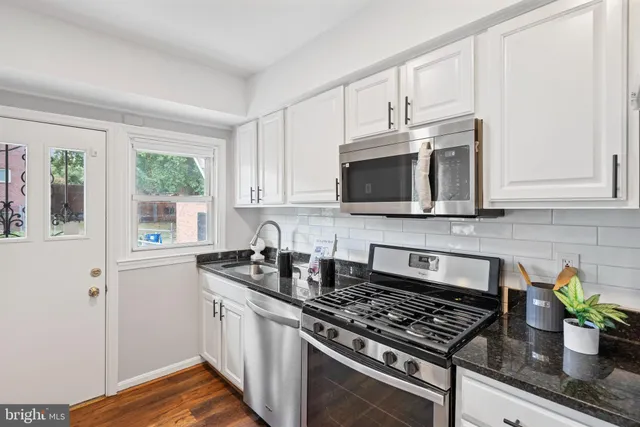 a kitchen with stainless steel appliances granite countertop a stove a sink and a microwave