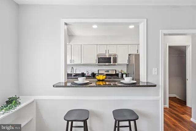 a kitchen with stainless steel appliances a sink a stove and white cabinets