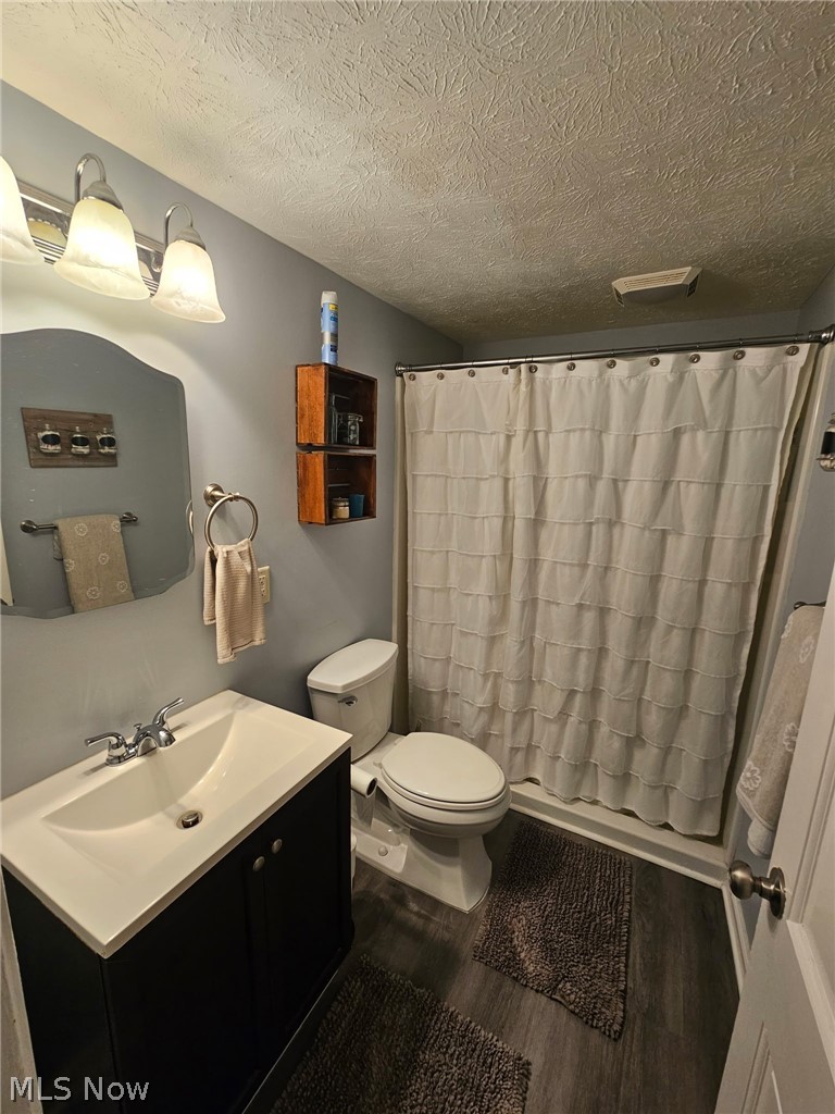 6620 West Lake Road Vermilion, OH 44089 - Photo 31 of 34 Bathroom featuring a single vanity with storage, undermount sink, chrome faucet, and wood-finish flooring