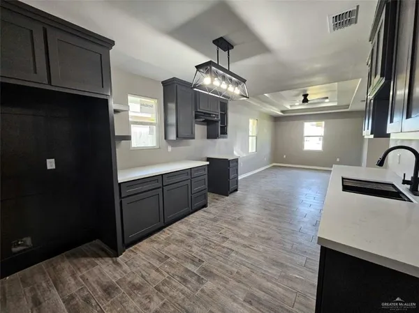 a large kitchen with stainless steel appliances granite countertop a sink dishwasher a stove and a refrigerator with wooden floor