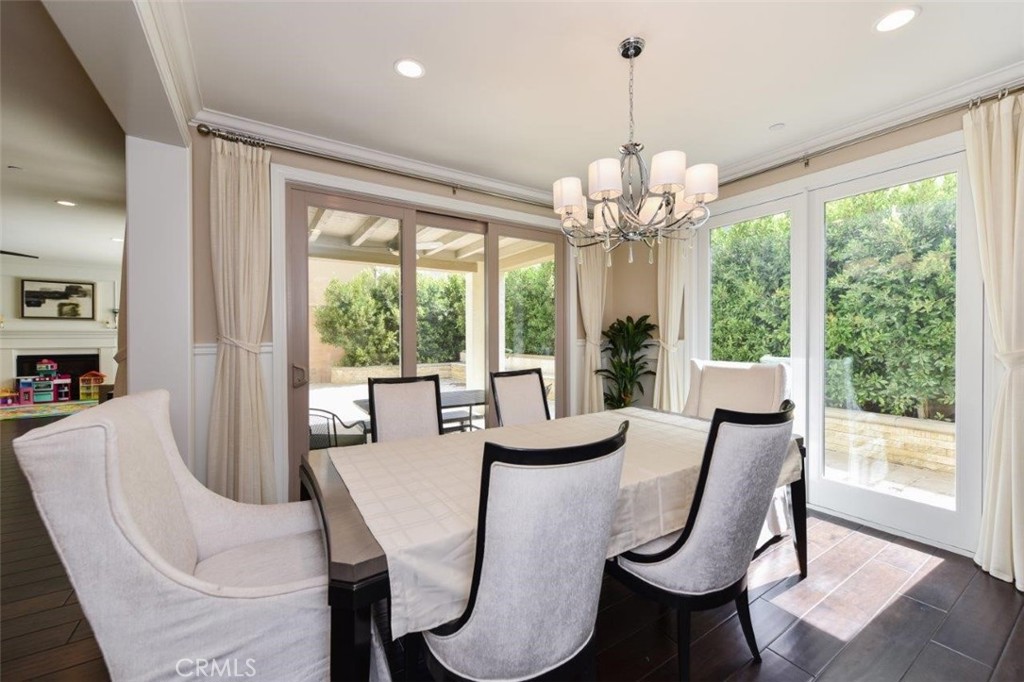 62 Rossmore Irvine, CA 92620 - Photo 34 of 43 a dining room with wooden floor a chandelier a glass table and chairs