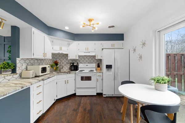 a kitchen with granite countertop white cabinets and white appliances