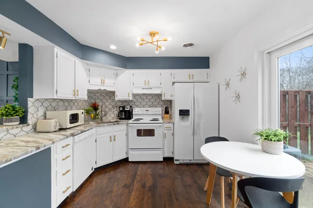 a kitchen with granite countertop white cabinets and white appliances