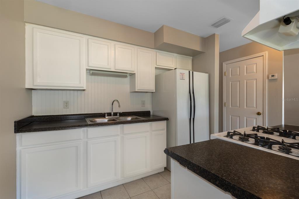2436 Northland Road Mount Dora, FL 32757 - Photo 6 of 27 a kitchen with granite countertop a sink stove and refrigerator