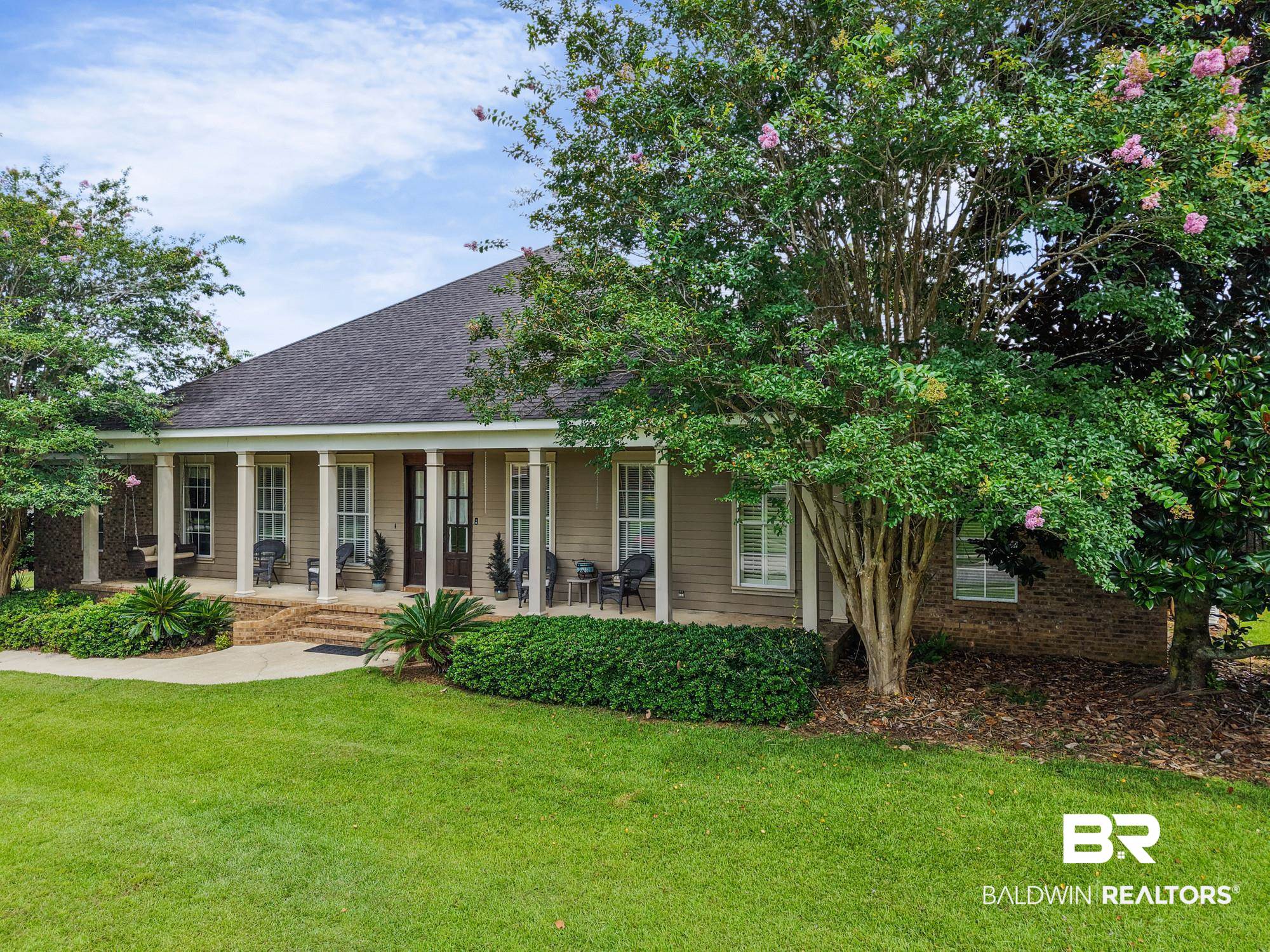 11261 Halcyon Loop Daphne, AL 36526 - Photo 3 of 41 Traditional-style home featuring a covered front porch with white columns, tan siding, and a dark shingled roof