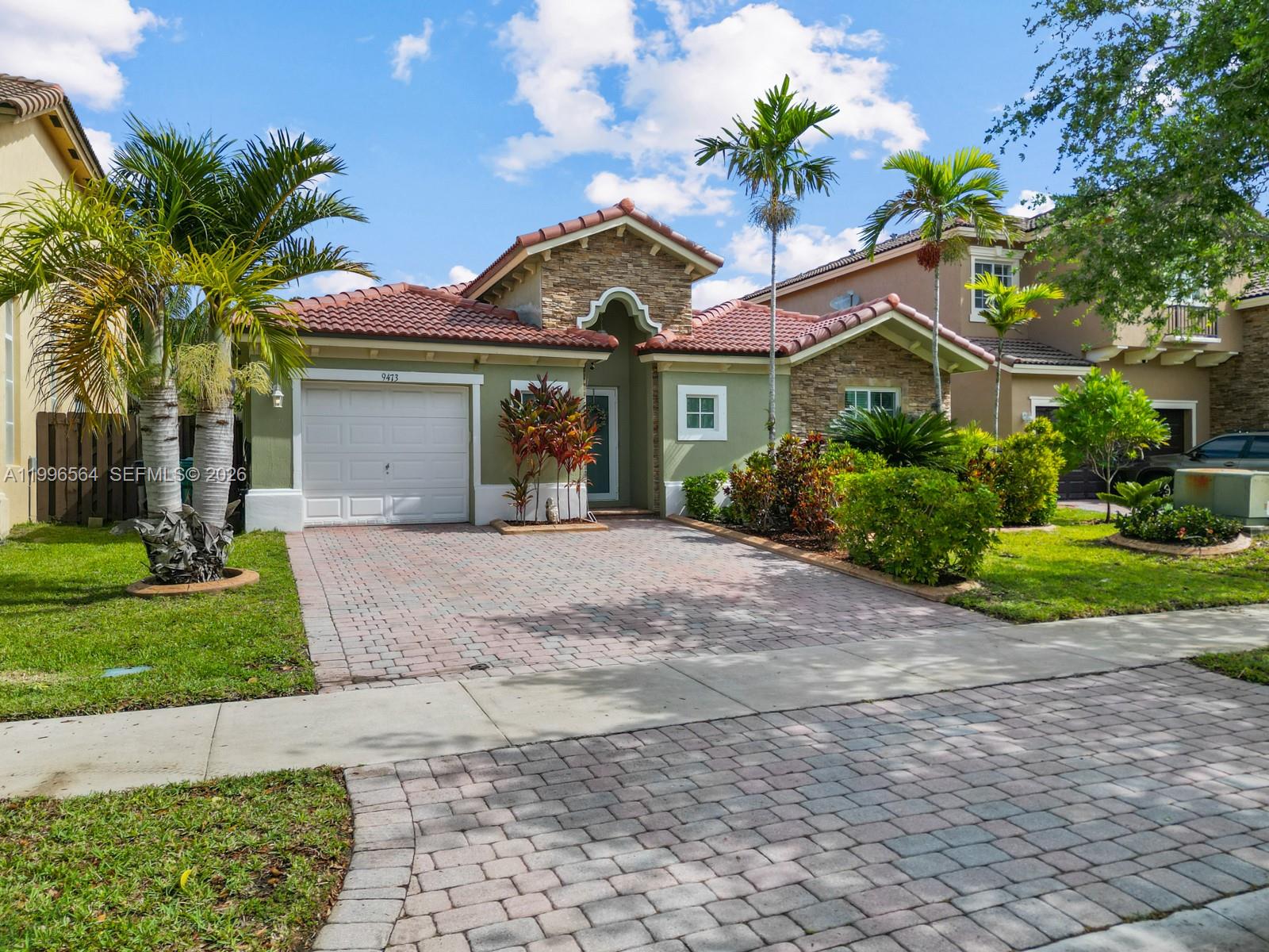 9473 Southwest 227th Terrace Cutler Bay, FL 33190 - Photo 1 of 31 a front view of a house with a garden and trees