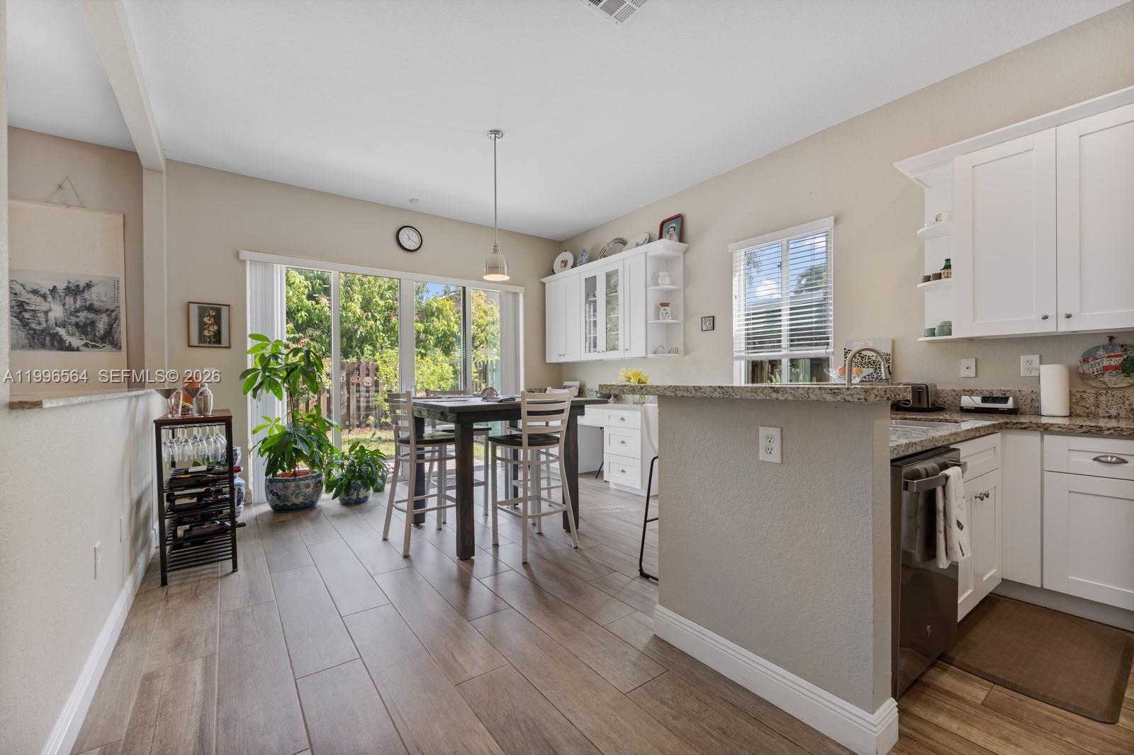 9473 Southwest 227th Terrace Cutler Bay, FL 33190 - Photo 11 of 31 a kitchen with stainless steel appliances a table chairs refrigerator and a wooden floor