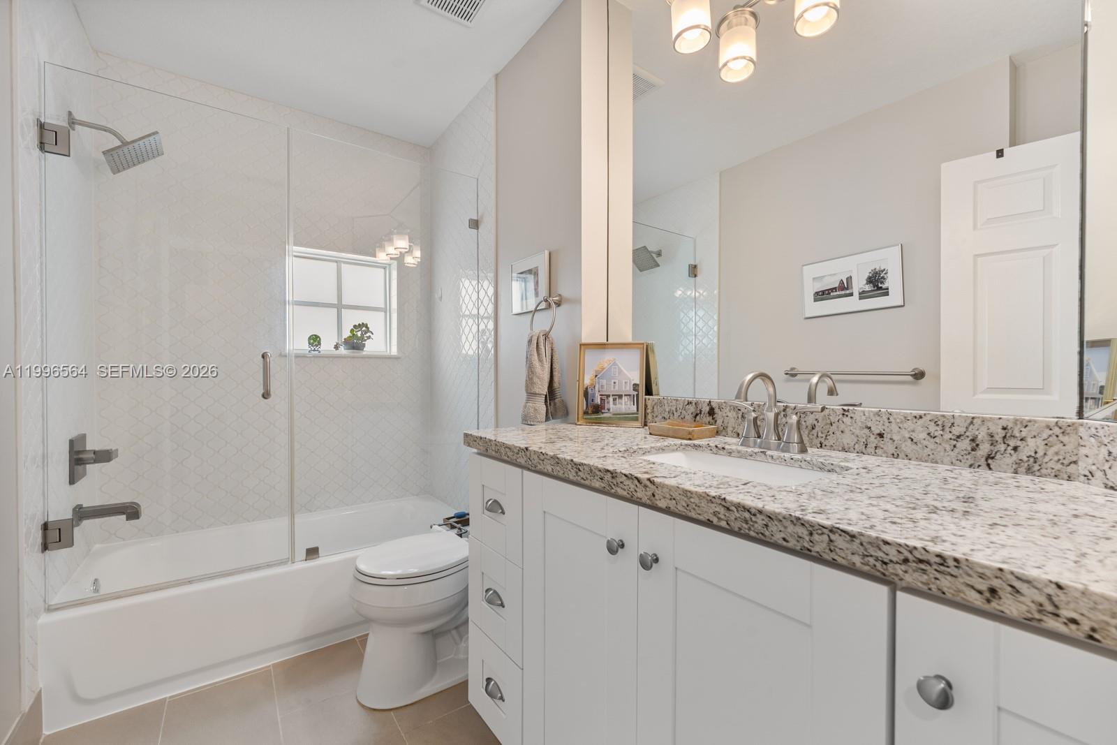 9473 Southwest 227th Terrace Cutler Bay, FL 33190 - Photo 19 of 31 a bathroom with a granite countertop sink a toilet and bathtub