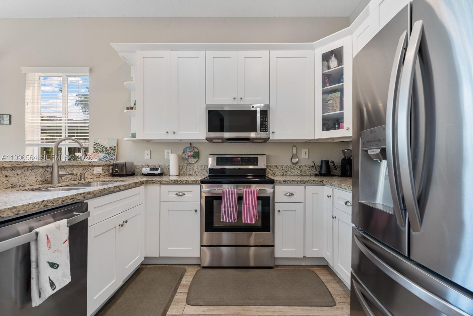 9473 Southwest 227th Terrace Cutler Bay, FL 33190 - Photo 10 of 31 a kitchen with stainless steel appliances granite countertop a stove a sink and a refrigerator