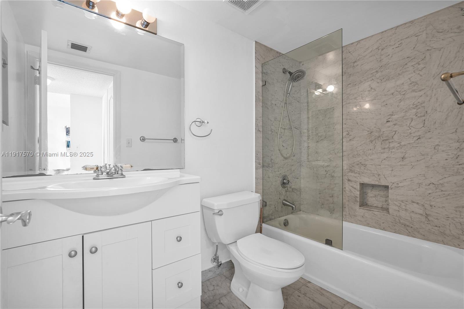 9455 Collins Avenue, Unit 603 Surfside, FL 33154 - Photo 16 of 22 a bathroom with a bathtub shower sink mirror vanity and toilet