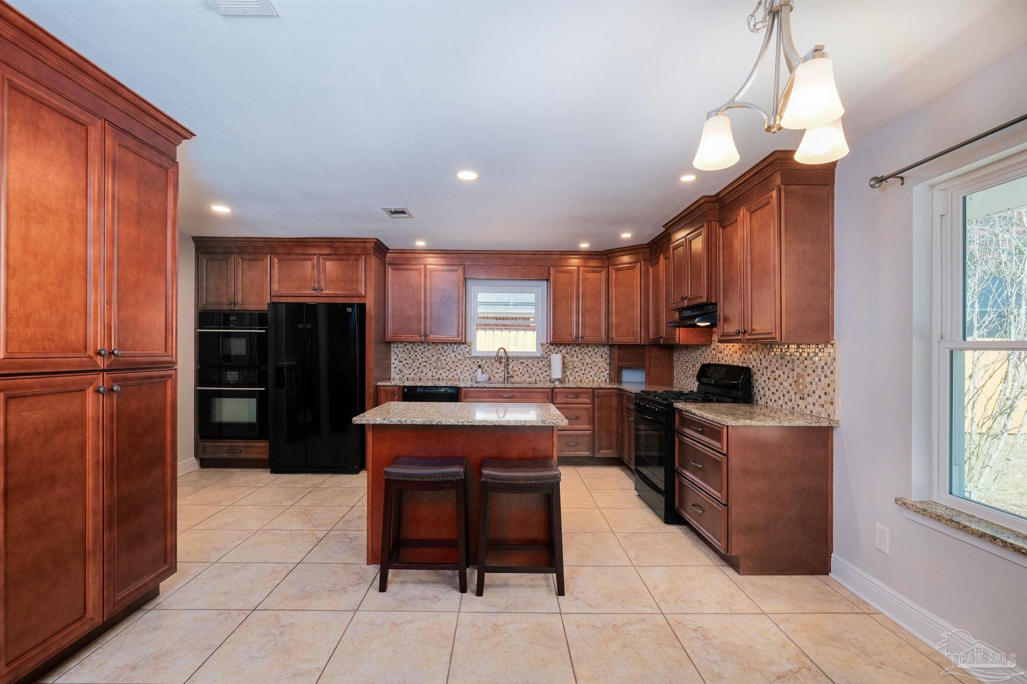 1908 Joshua Drive Cantonment, FL 32533 - Photo 10 of 47 a kitchen with stainless steel appliances granite countertop a refrigerator a sink a stove and island