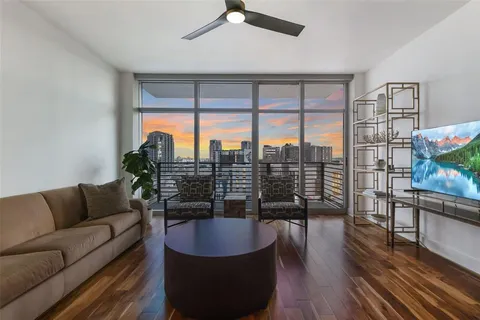 a living room with furniture a floor to ceiling window and wooden floor