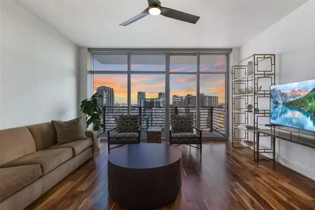 a living room with furniture a floor to ceiling window and wooden floor