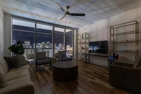 a living room with furniture a flat screen tv and floor to ceiling window