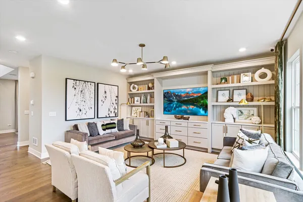 a living room with furniture a flat screen tv and floor to ceiling window