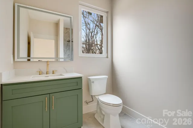a bathroom with a toilet sink vanity and mirror