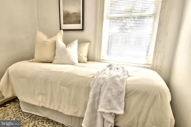 a large white bed sitting in a bathroom next to a window