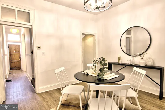 a dining room with wooden floor a chandelier a wooden table and chairs