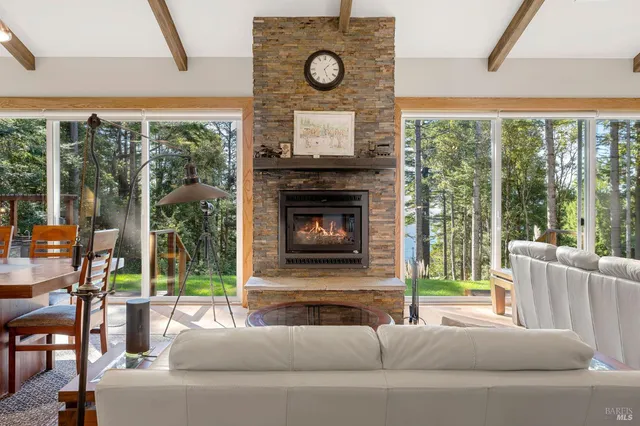 a living room with furniture a fireplace and floor to ceiling windows