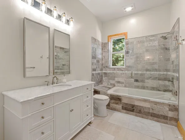 a bathroom with a double vanity sink a toilet and a bathtub