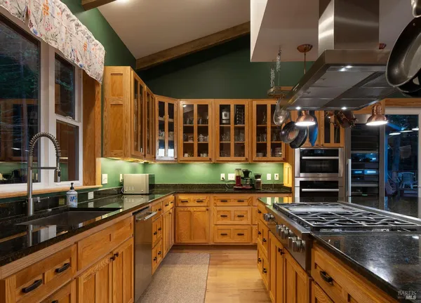 a kitchen with stainless steel appliances granite countertop a sink a stove and a wooden floors