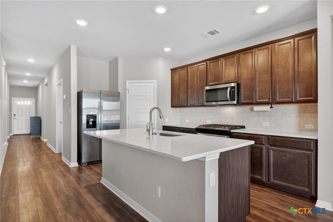 1036 View Drive Georgetown, TX 78628 - Photo 6 of 33 a kitchen with a sink a microwave a refrigerator and cabinets