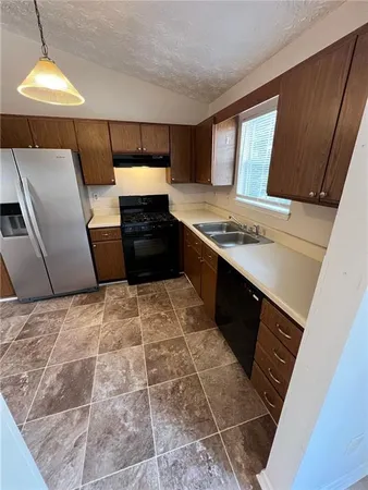 a kitchen with granite countertop a refrigerator and a stove top oven