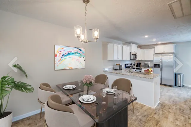 a kitchen with stainless steel appliances granite countertop a refrigerator a stove a sink dishwasher and white cabinets with wooden floor