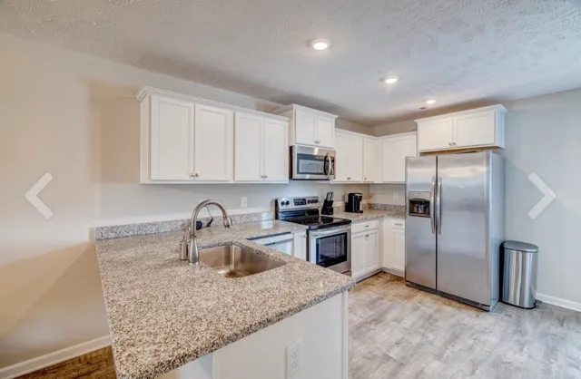 a kitchen with kitchen island granite countertop a sink a stove a refrigerator and cabinets