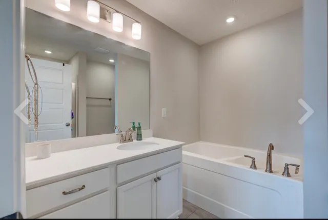 a bathroom with a bathtub sink vanity and mirror