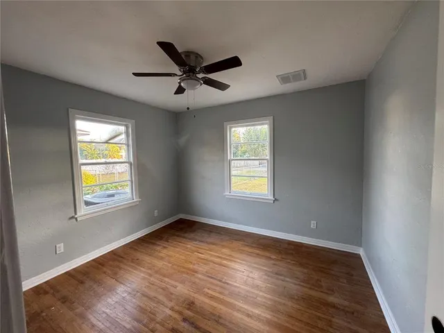 a view of empty room with wooden floor and fan
