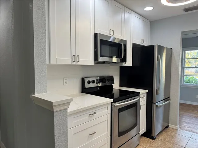 a kitchen with stainless steel appliances granite countertop white cabinets a refrigerator and a stove