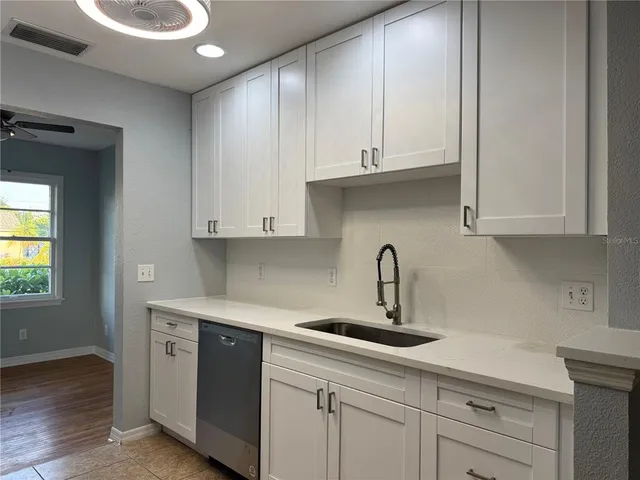 a kitchen with white cabinets and sink