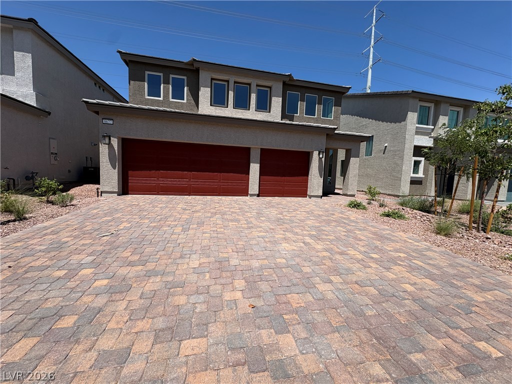 8677 South Indigo Springs Road Las Vegas, NV 89139 - Photo 1 of 9 A contemporary residence showcasing a paver driveway and a two-car garage with rich red doors.