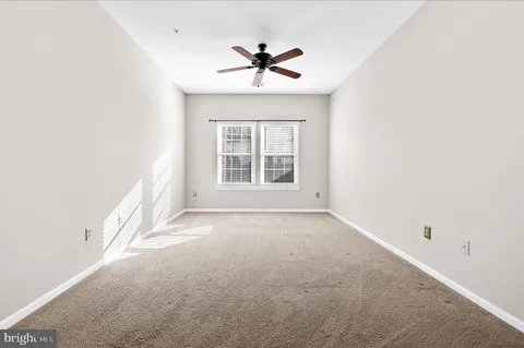 an empty room with a window and a ceiling fan