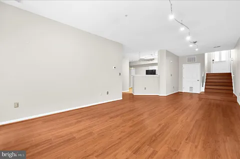 an empty room with wooden floor and bathroom view
