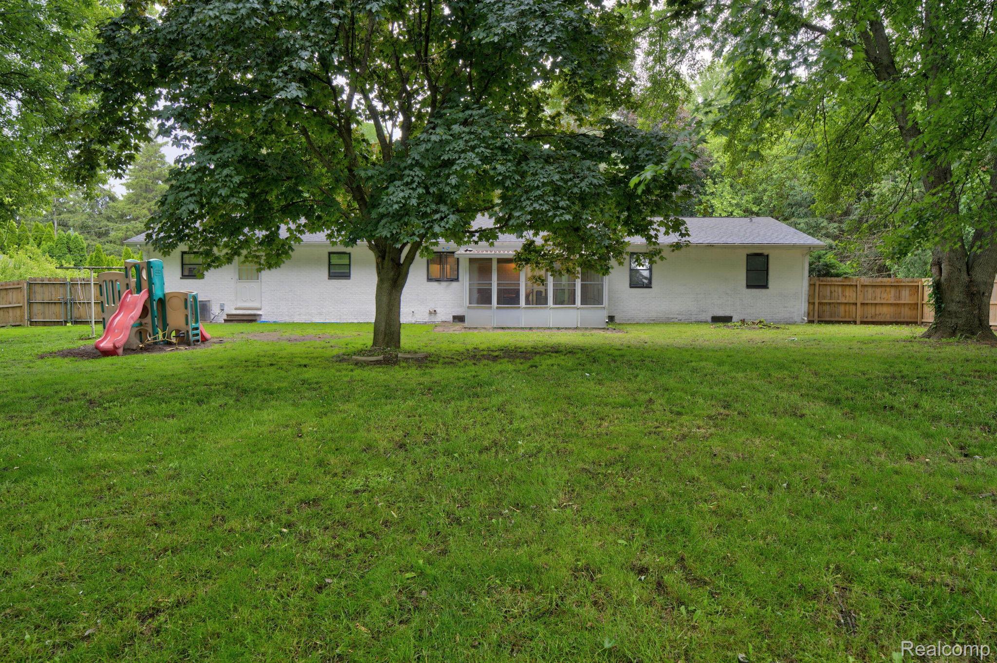 5330 Sheridan Road Saginaw, MI 48601 - Photo 43 of 50 Expansive rear yard featuring a manicured lawn, established shade trees, and a full privacy fence