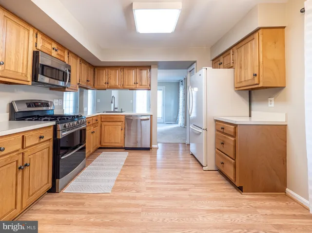 a kitchen with stainless steel appliances granite countertop wooden floors and white cabinets