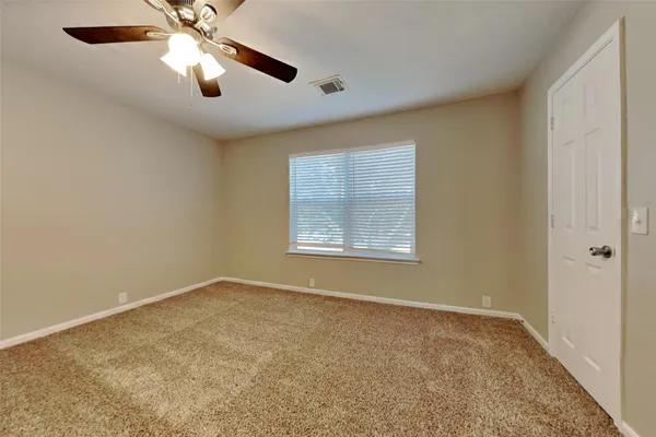 an empty room with a window and a fan