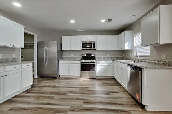 a kitchen with granite countertop white cabinets and stainless steel appliances